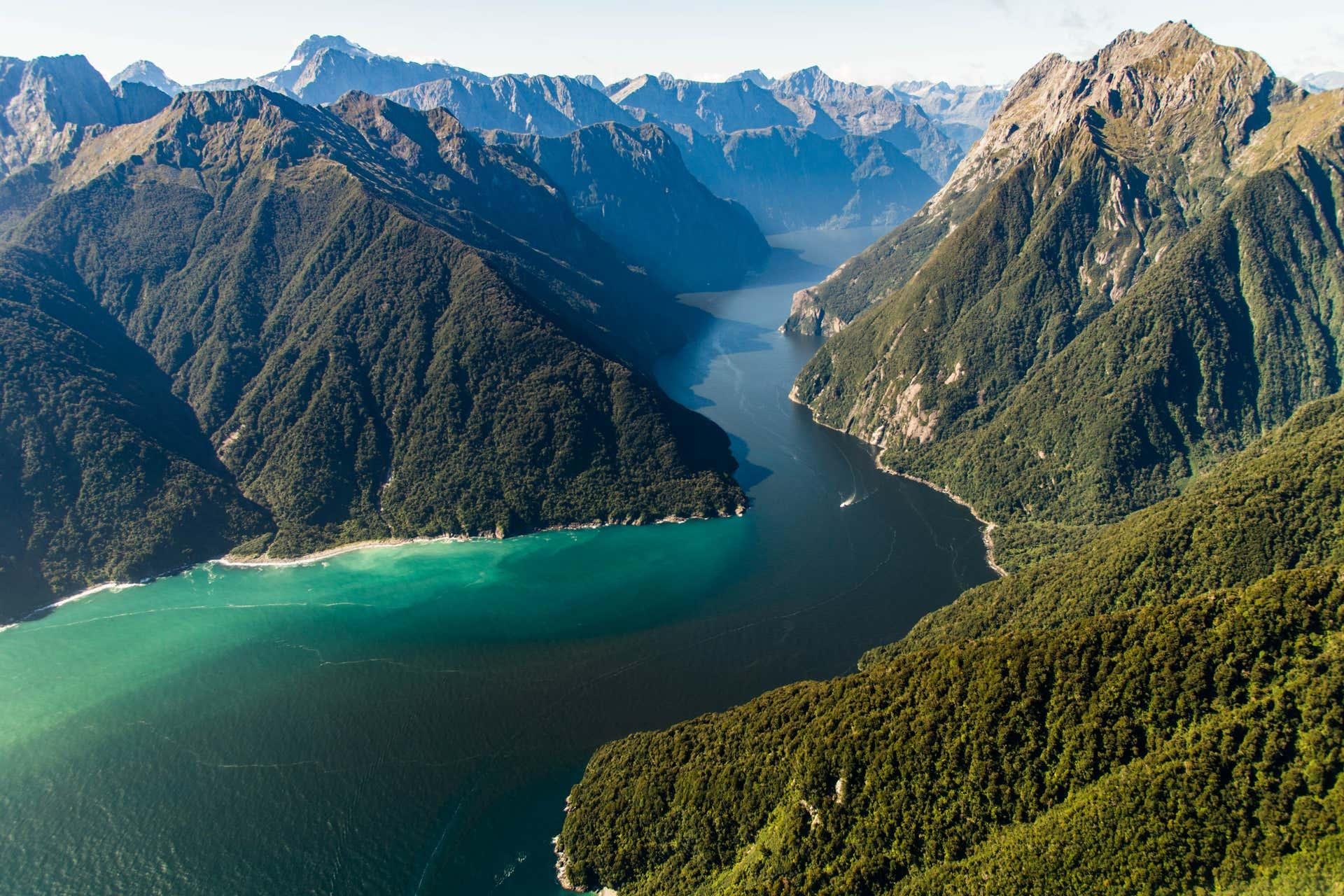 Aerial view of a green fjord valley and turquoise water on the way to Milford Sound, New Zealand.