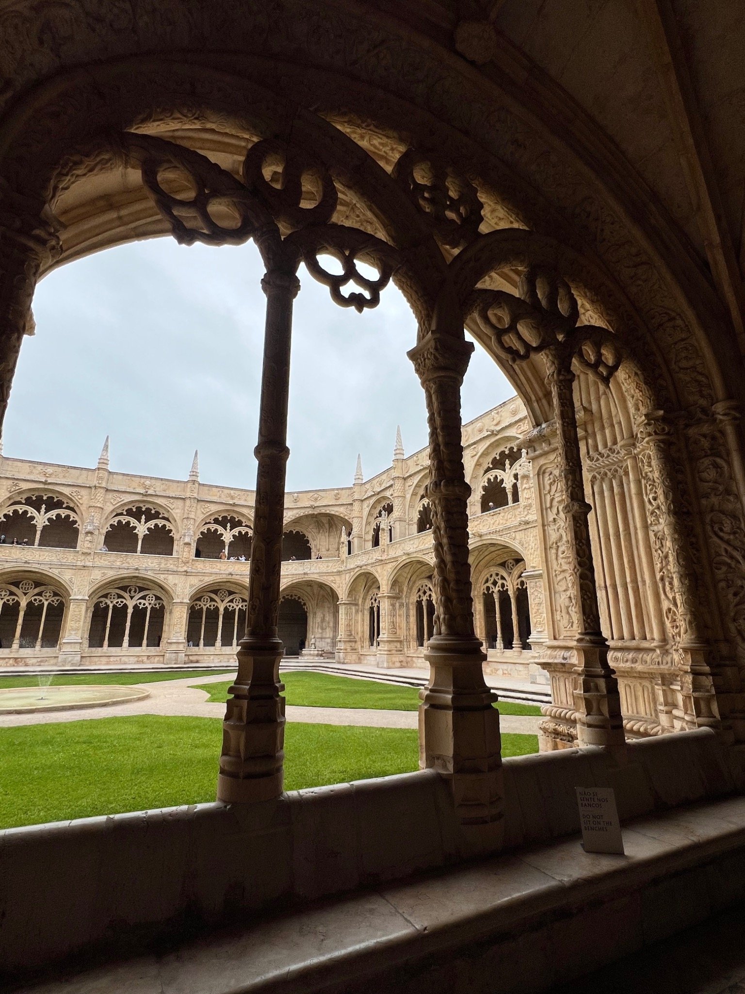 Ornate Manueline stone tracery framing a view of the cloister courtyard at Jerónimos Monastery, Lisbon.